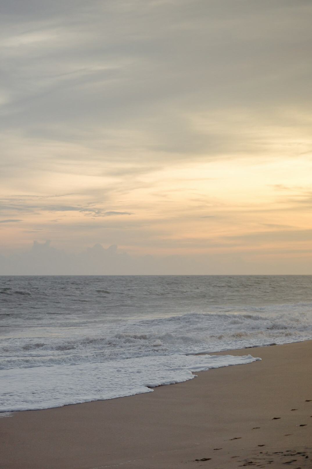 Wide sandy beach with calm sea at sunrise
