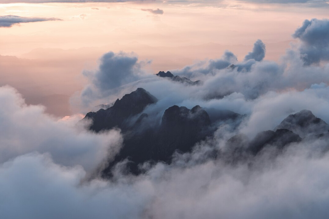Snowy mountain peaks above clouds at sunrise