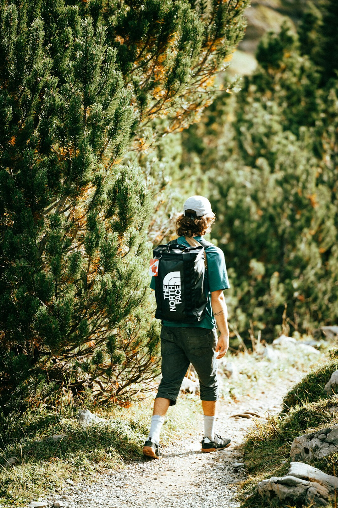 Hiker with backpack standing on a mountain trail