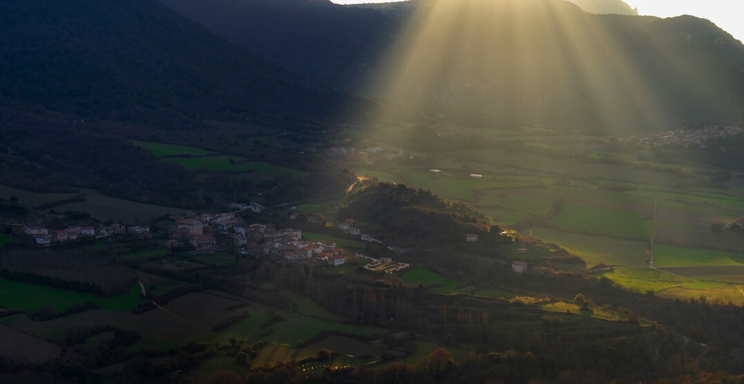 Sun rays over a green valley and mountains